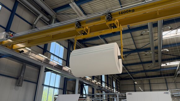 The two electric chain hoists of the overhead crane work together to lift the load beam carrying the paper roll.